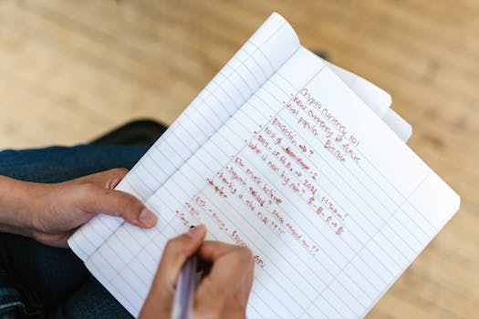 A person writing cryptocurrency notes in a notebook, highlighting Bitcoin and future predictions.