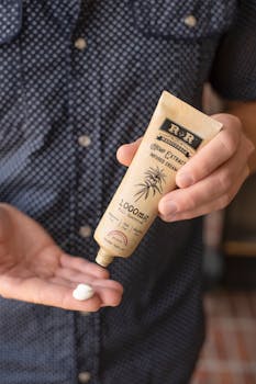 Close-up of a person applying hemp-infused cream from a tube onto their hand.