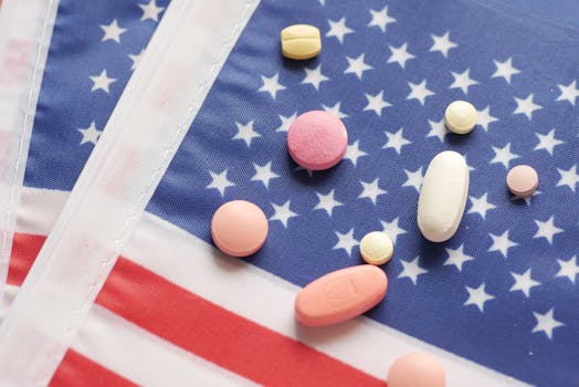 Various pills scattered over a printed American flag symbolizing healthcare.